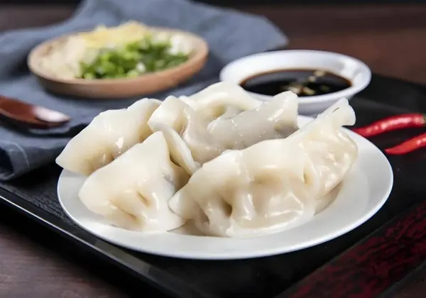 Handmade Chinese dumplings arranged on a plate, crescent-shaped